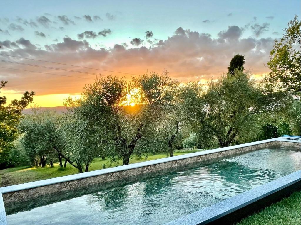 una piscina en un jardín con una puesta de sol en el fondo en Agriturismo CasaViVa, en Pozzo
