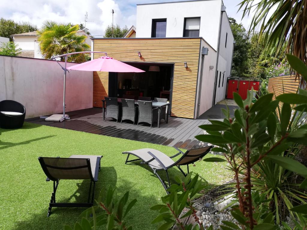un patio avec une table, des chaises et un parasol dans l'établissement coin de paradis 3 chambres, à Fouras