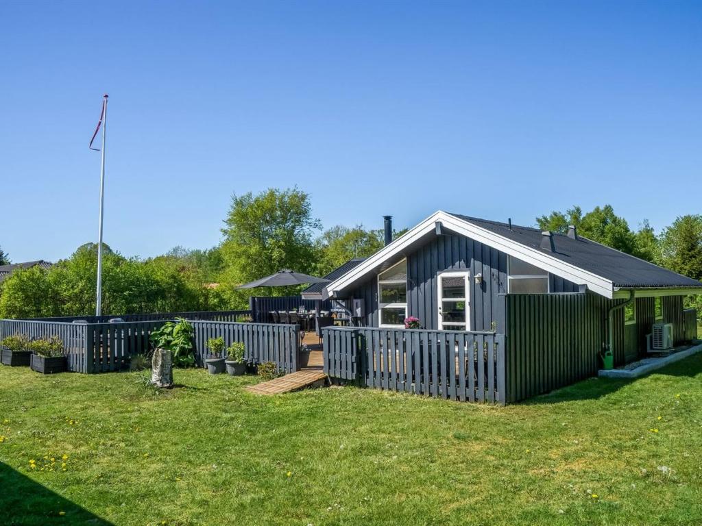 a small house with a fence in a yard at Holiday Home Bryti - 500m from the sea in NE Jutland by Interhome in Hals
