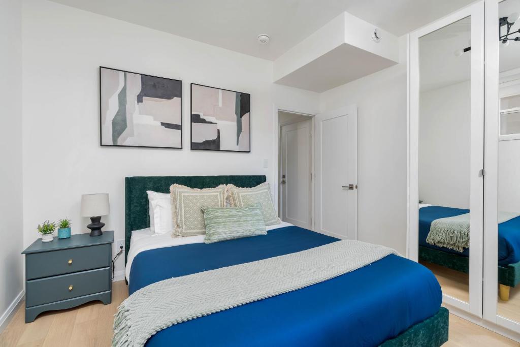 a bedroom with a blue bed and a mirror at Spacious 3BDR Sleeps 6 with Patio By Little Italy! in Toronto