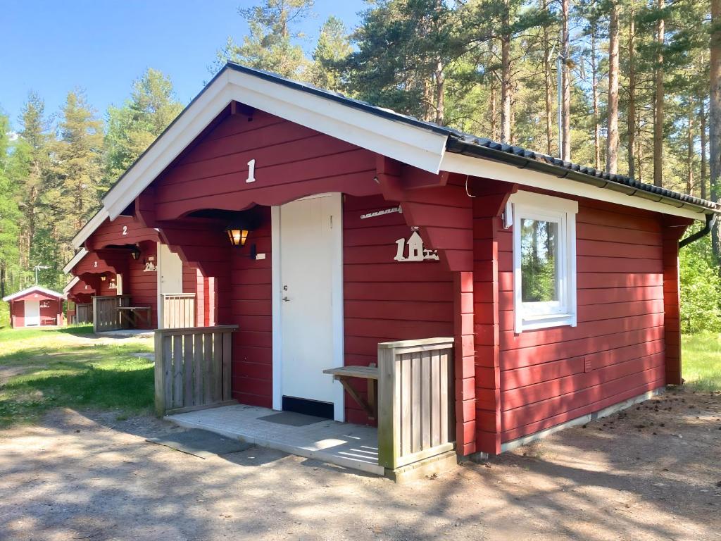 een rode schuur met een witte deur en een veranda bij Hyltena Stugby in Jönköping