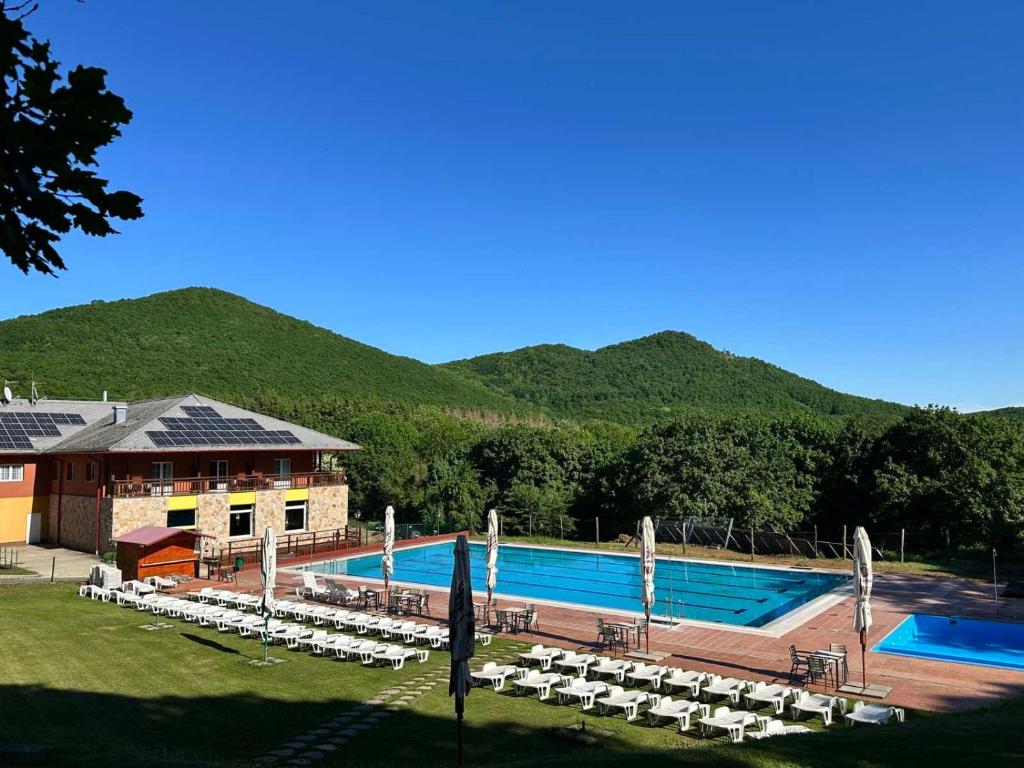 ein großer Pool mit Stühlen und ein Gebäude in der Unterkunft Szent Orbán Erdei Wellness Hotel in Kóspallag