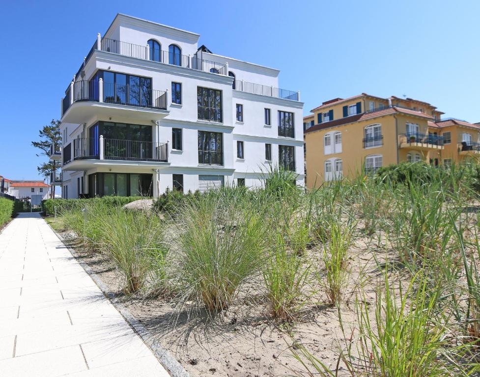 a white building on the beach with a sidewalk at Strandvilla Andrea Whg 07 Meerblick mit Balkon in Baabe