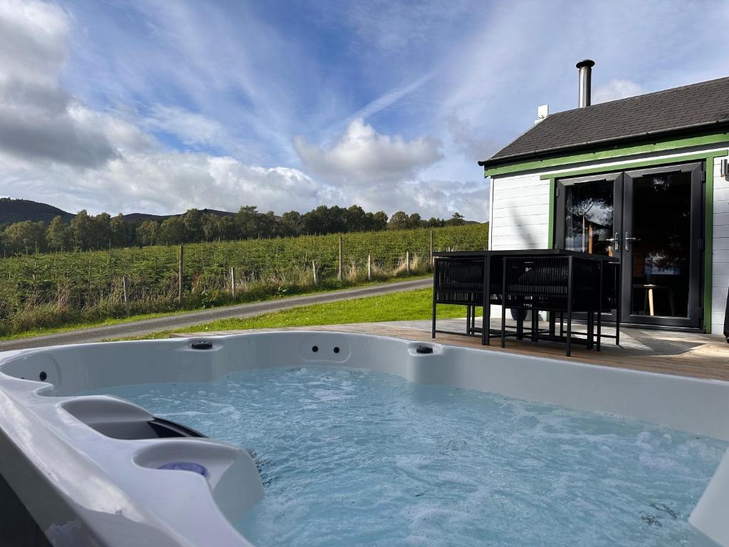 a hot tub with a piano next to a house at Kinnaird Woodland Lodges in Pitlochry