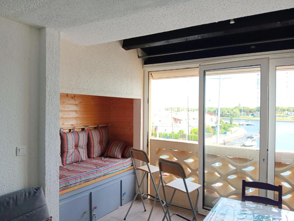 un balcon avec un canapé, une table et des chaises dans l'établissement Appartement lumineux à Agde avec vue sur la mer - 34 m², au Cap d'Agde