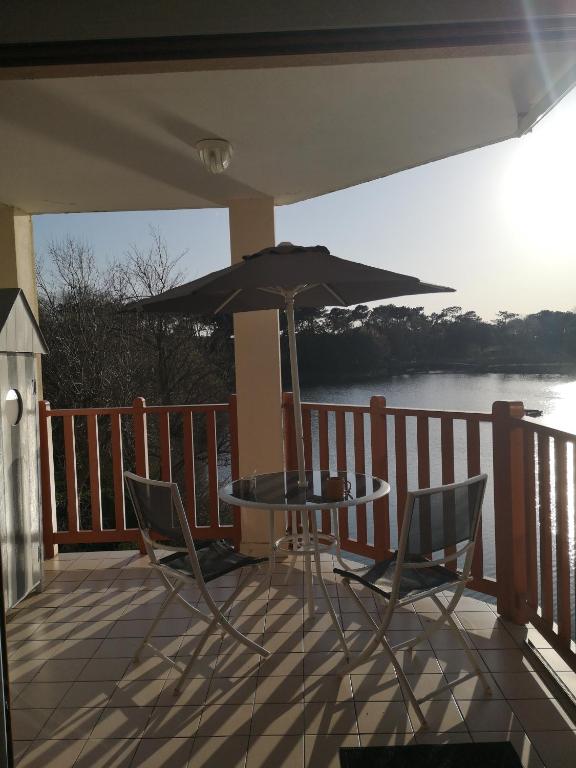 un patio avec une table, des chaises et un parasol dans l'établissement l'orée du lac, à Talmont-Saint-Hilaire