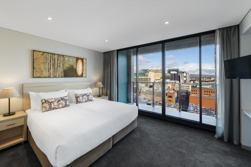 a bedroom with a large bed and a large window at Oaks Adelaide Horizons Suites in Adelaide
