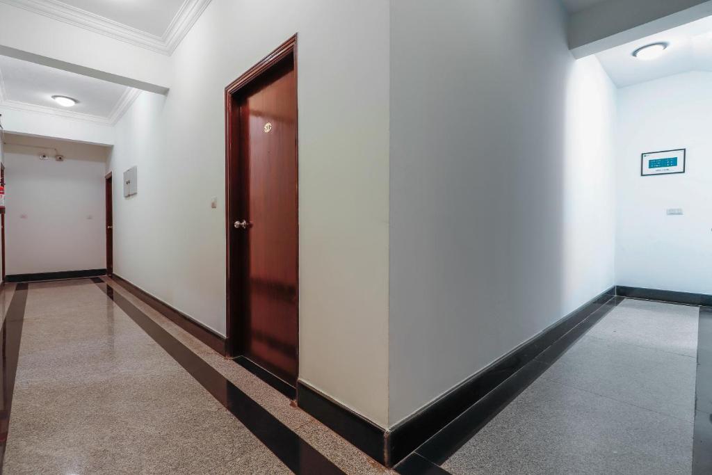 a corridor with white walls and a wooden door at Emara Grand Hotel in Bangalore