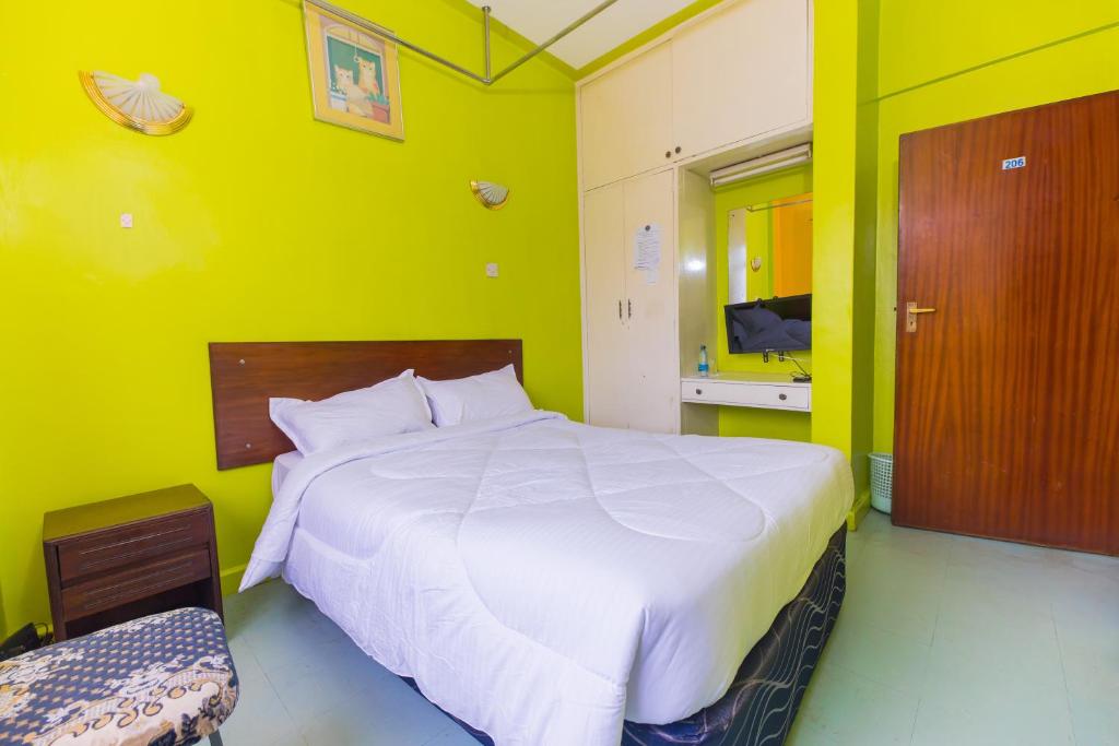 a bedroom with a large white bed and a green wall at Hotel Southern Blue in Nairobi