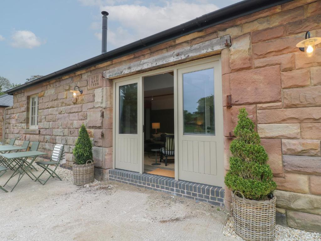 ein Steingebäude mit einer Tür, einem Tisch und Stühlen in der Unterkunft Holly Cottage - Fold Yards in Belper
