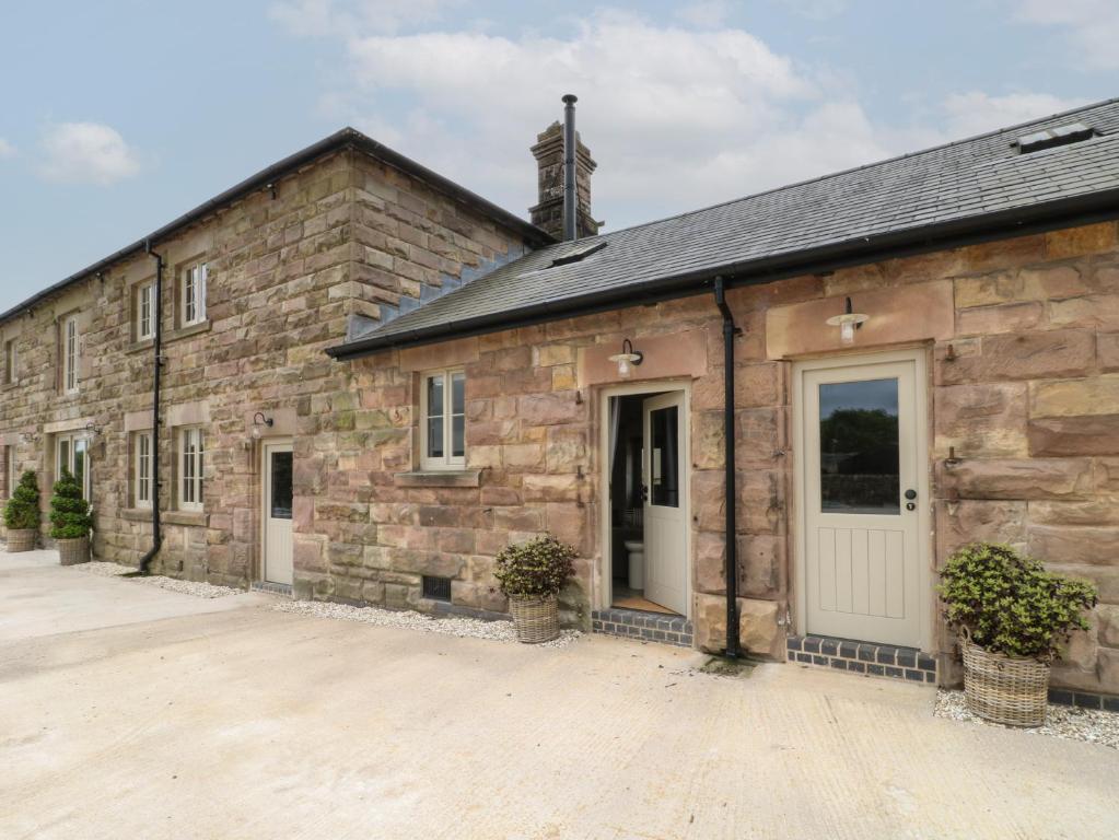 an old stone building with a white door at Hazel Cottage - Fold Yards in Belper