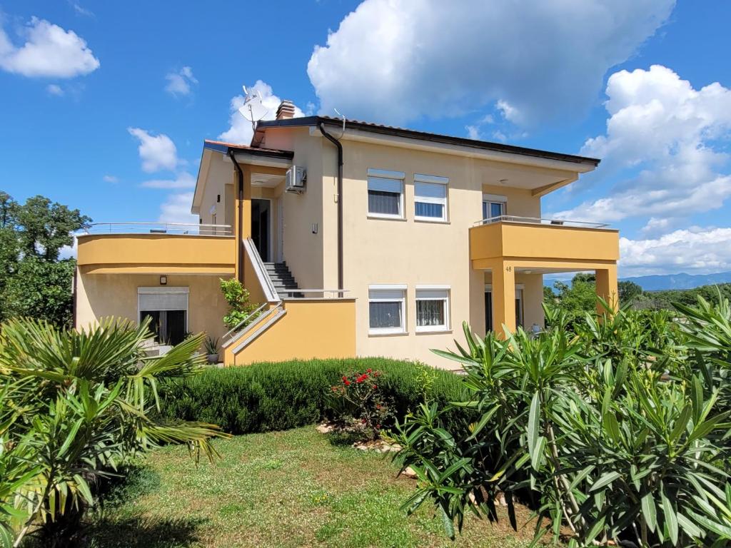 a yellow house with bushes in front of it at Apartmani Dani in Sveti Anton