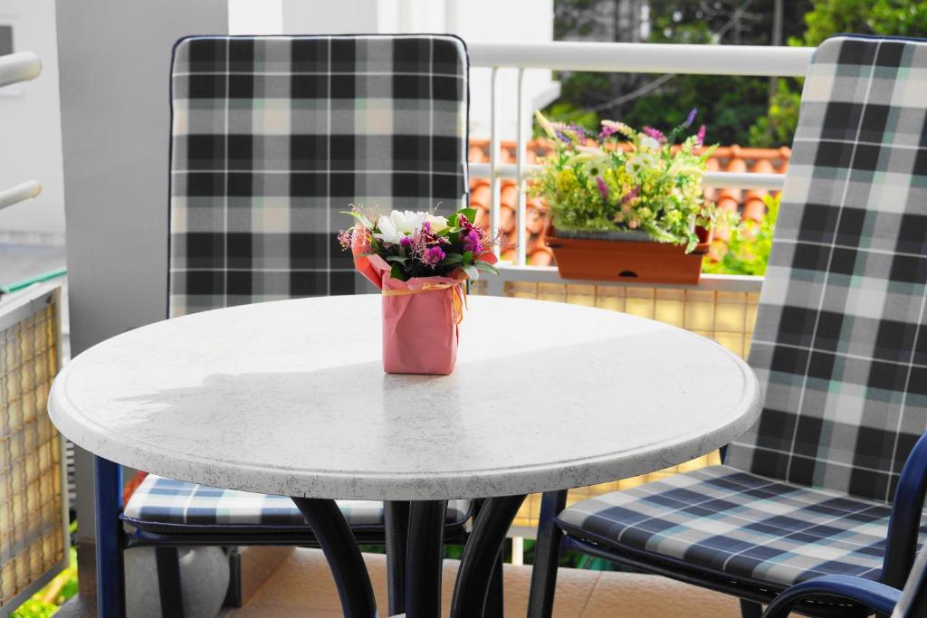 a table with two chairs and a vase of flowers at Apartman Mare in Dramalj