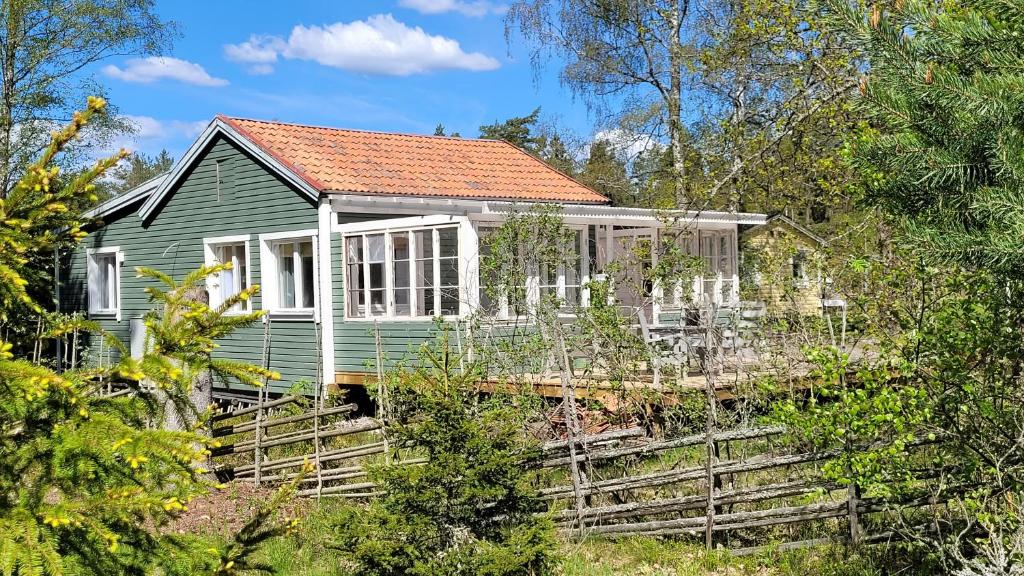 ein grünes Haus mit rotem Dach in der Unterkunft Mysig stuga i Svärtinge in Svärtinge