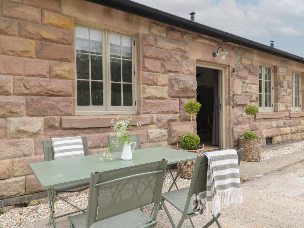 a table and chairs in front of a stone building at Oak Cottage - Fold Yards in Belper