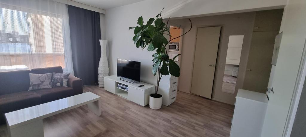 uma sala de estar com um sofá e um vaso de plantas em Linnankatu Apartment em Savonlinna