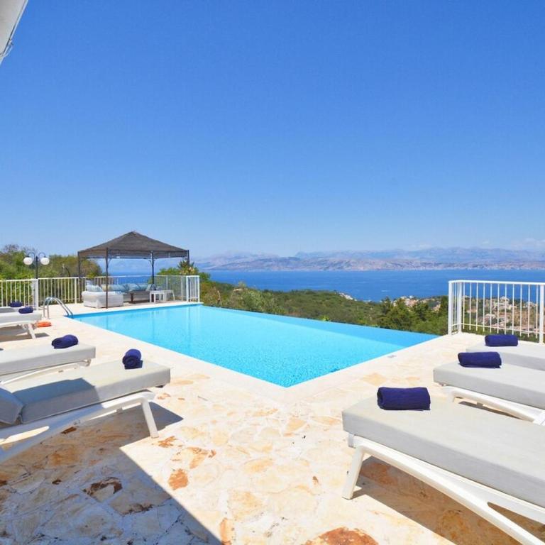 una piscina con sedie a sdraio e vista sull'oceano di Villa Helion Heated Pool a Kelliá