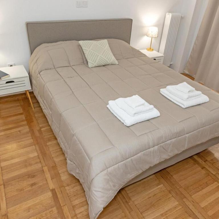 uma cama grande com duas toalhas em cima em Cozy Apartment in Kallithea em Atenas