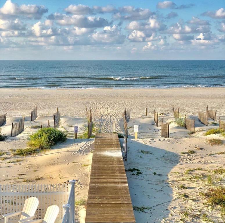 a wooden boardwalk on a beach with chairs and the ocean at Coastal Cove by Pristine Properties Vacation Rentals in Indian Pass