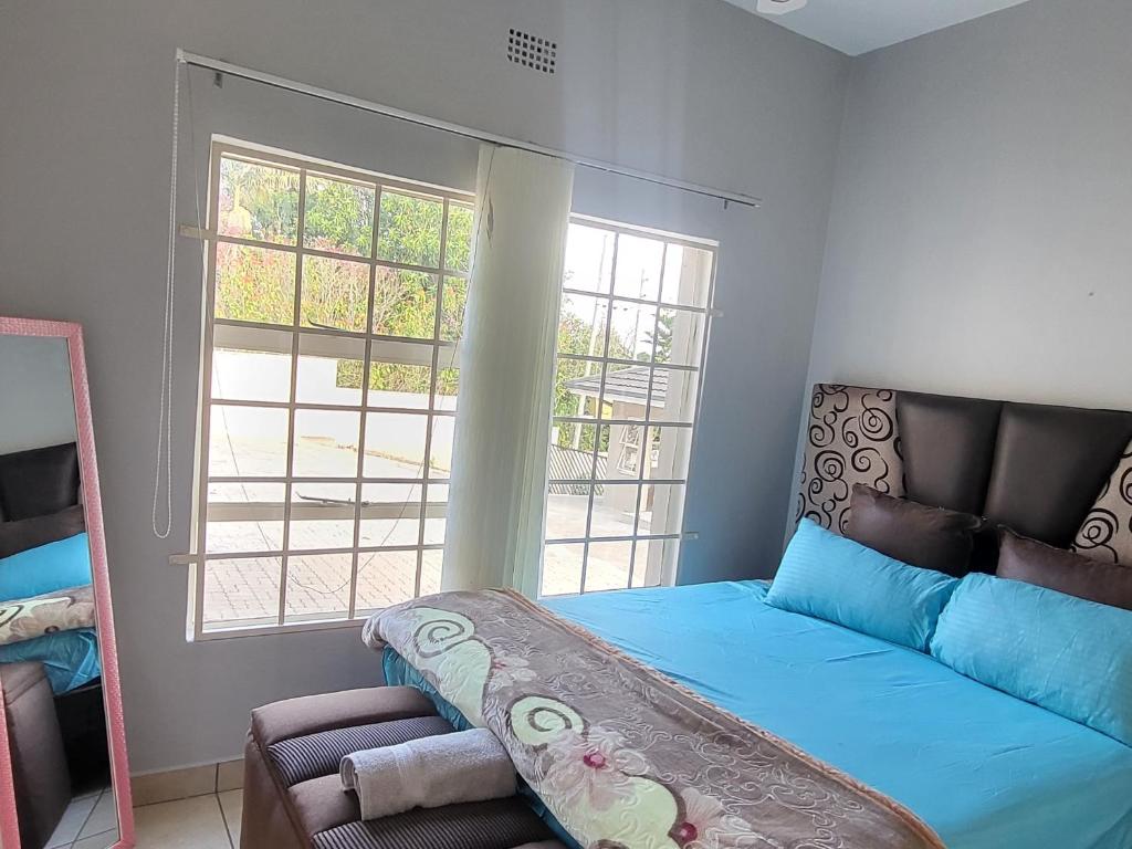 um quarto com uma cama azul e uma janela em ENTIRE LUXURY APARTMENTS em Mbabane