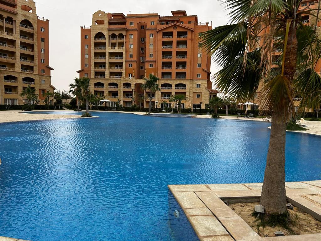 duży niebieski basen z budynkami w tle w obiekcie Marina valley high standard studio w mieście El Alamein