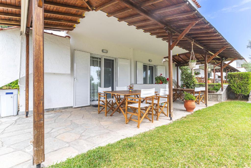 patio ze stołem i krzesłami pod pergolą w obiekcie Mola Kalyva Suites w mieście Mola Kalyva
