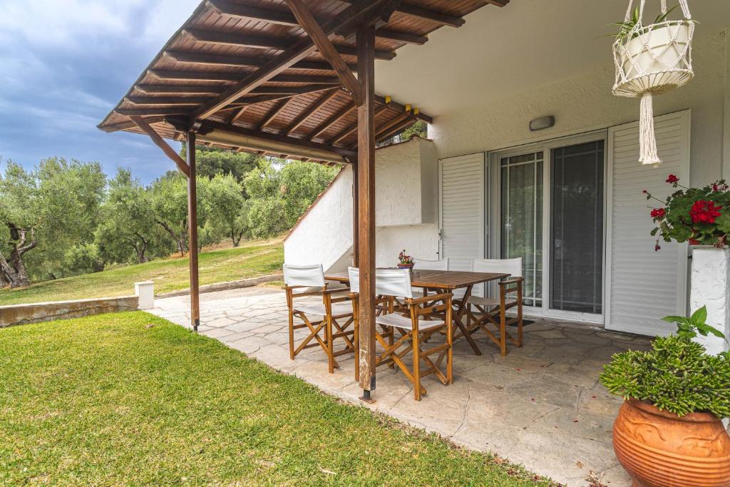 patio ze stołem i krzesłami pod drewnianą pergolą w obiekcie Mola Kalyva Suites w mieście Mola Kalyva