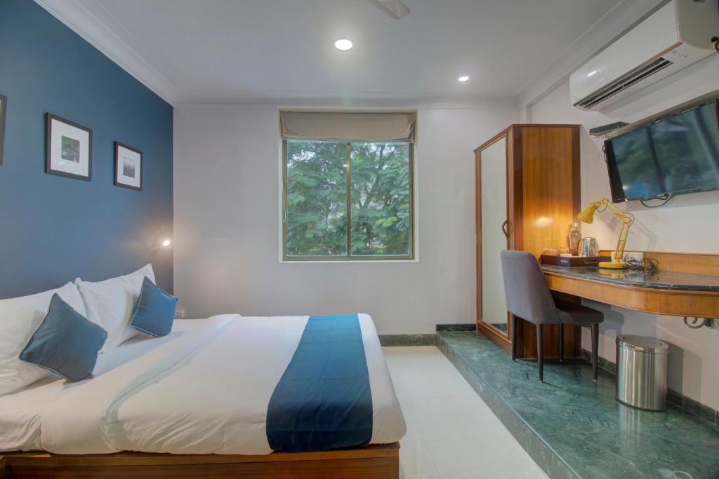 OYO SilverKey Hotel Manas Residency في مومباي: غرفة نوم بسرير ومكتب ونافذة