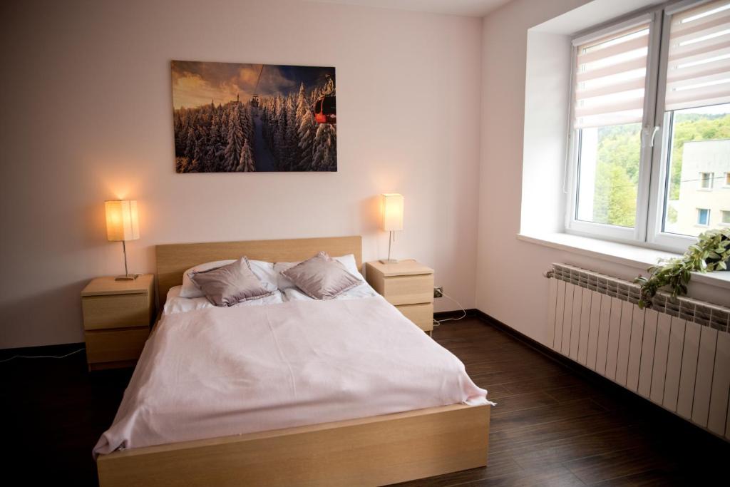 クリニツァ・ズドルイにあるGo2Krynica - Deptakのベッドルーム1室(ベッド1台、ナイトスタンド2台、窓2つ付)