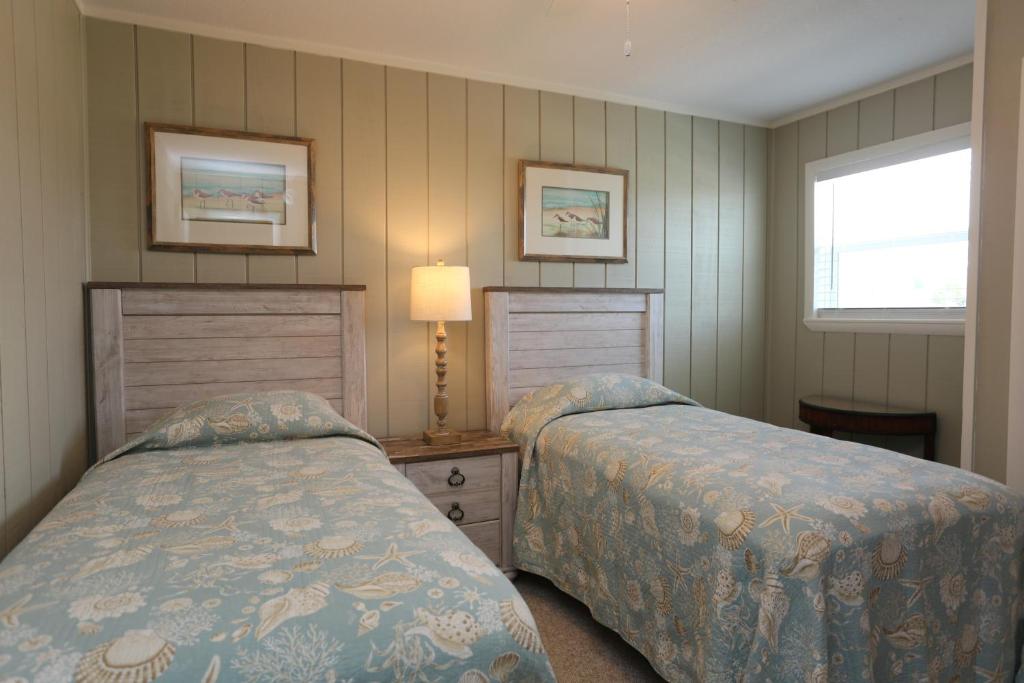 a bedroom with two beds and a lamp and a window at One More Time Again by Pristine Properties Vacation Rentals in Mexico Beach