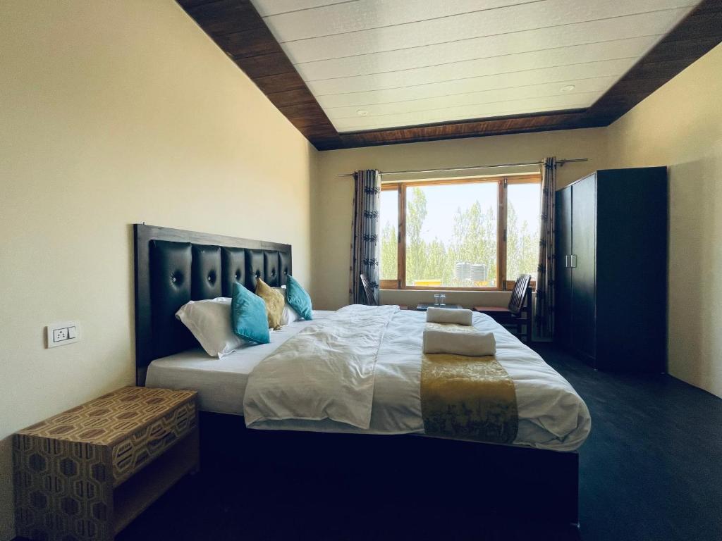 a bedroom with a large bed with a large window at Zlatan Guest House in Leh