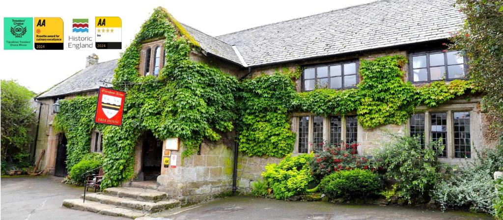 an ivy covered house with a sign in front of it at The Oxenham Arms Hotel Devon in South Zeal