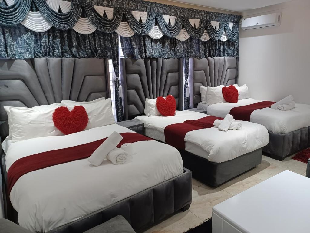 um quarto com três camas com corações vermelhos em Gold Crown International Hotel em Joanesburgo