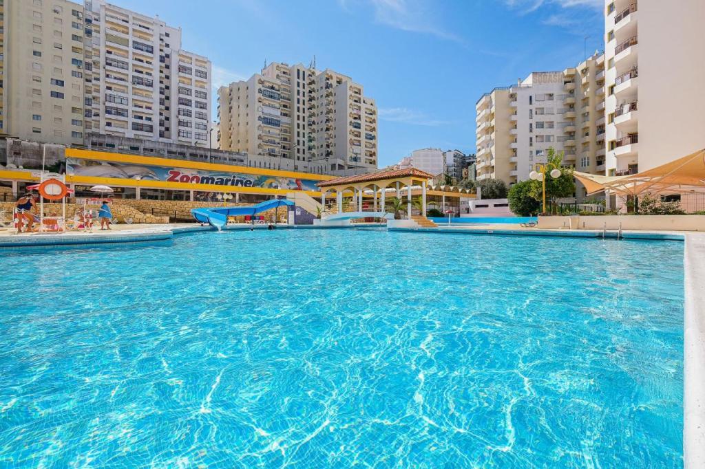 a large swimming pool in a city with tall buildings at Karol Vaz in Portimão