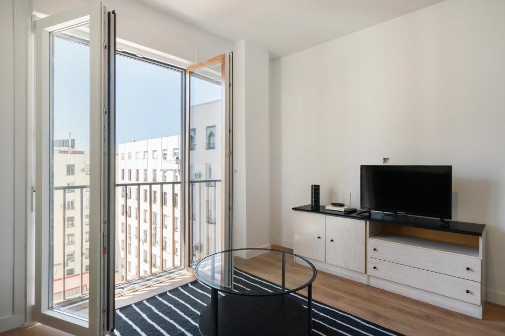 a living room with a tv and a large window at dobohomes - Fernandez de los rios in Madrid