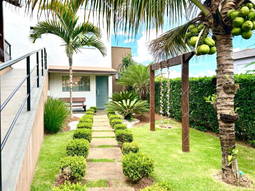 a garden with a palm tree and a walkway at Pousada Rainha Dos Lagos in Capitólio