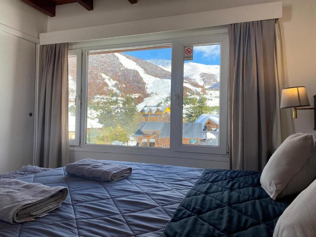 1 dormitorio con cama y ventana grande en Catedral Sur departamento en Bariloche en San Carlos de Bariloche