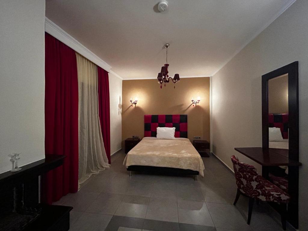1 dormitorio con cama y cortina roja en Faraggi Hotel, en Simvolí