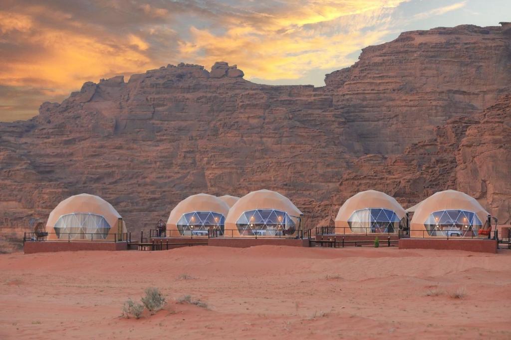a group of domes in the desert near a mountain at Faisal Wadi Rum camp in Wadi Rum