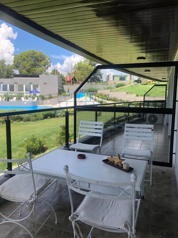 einen weißen Tisch und Stühle auf einer Terrasse mit einem Pool in der Unterkunft ALQUILER VENETO VILLAGE in Villa Parque Siquiman