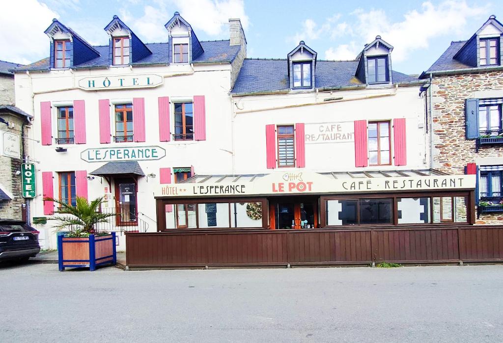 a large white building with red shutters on a street at Hôtel de l'Espérance in Saint-Cast-le-Guildo