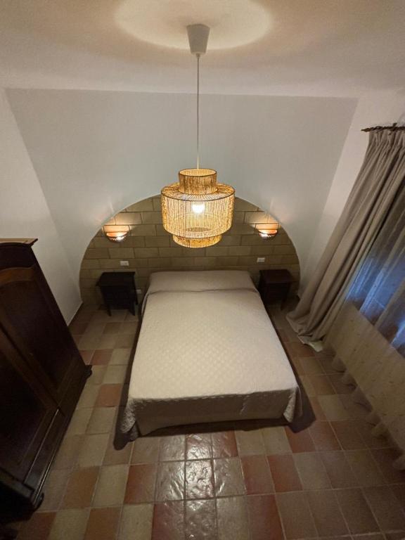 a bed in a room with a chandelier at B&B Villa Alba in San Vito lo Capo
