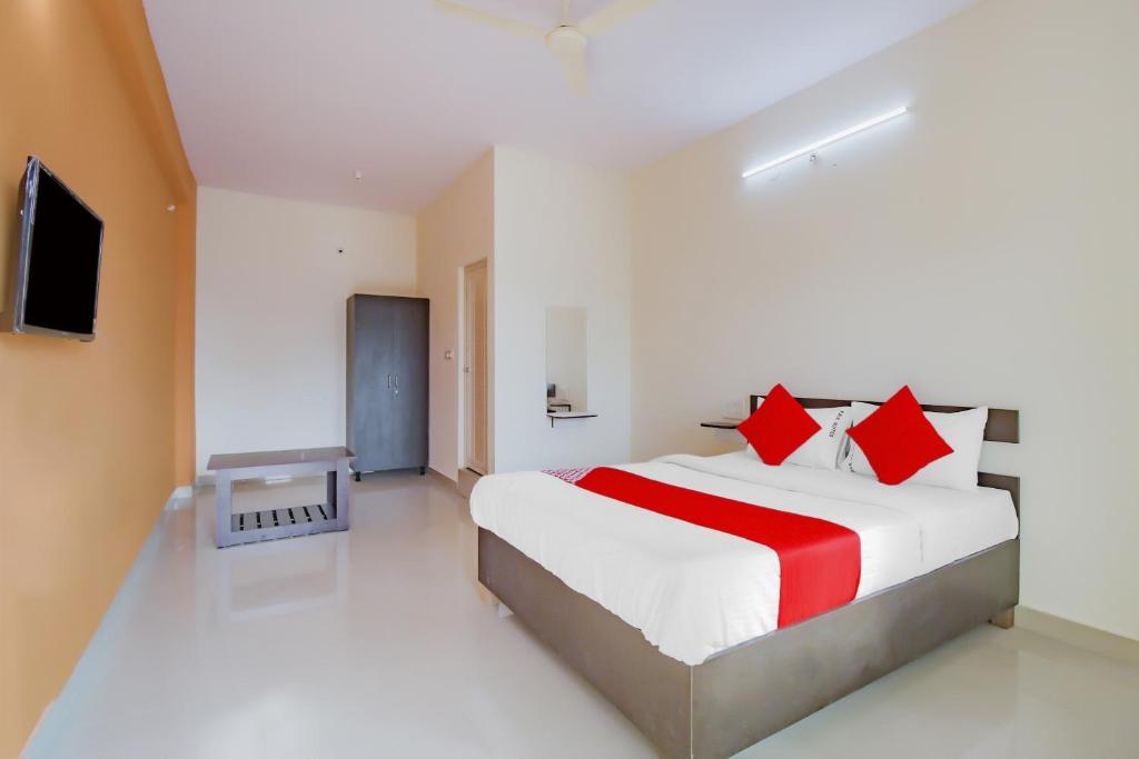 a bedroom with a large bed with red pillows at OYO Flagship 77067 P N K Suites in Jālahalli