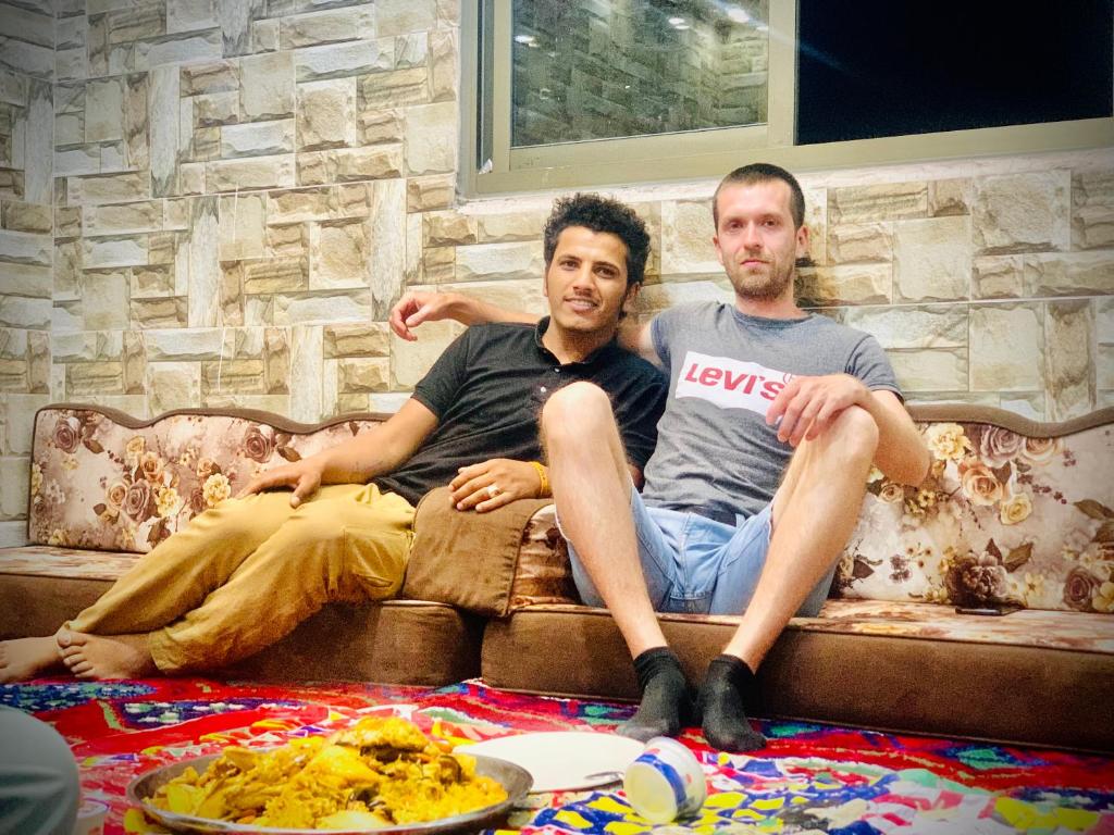 Dois homens sentados num sofá na sala de estar. em Bedouin Panorama House em Wadi Musa