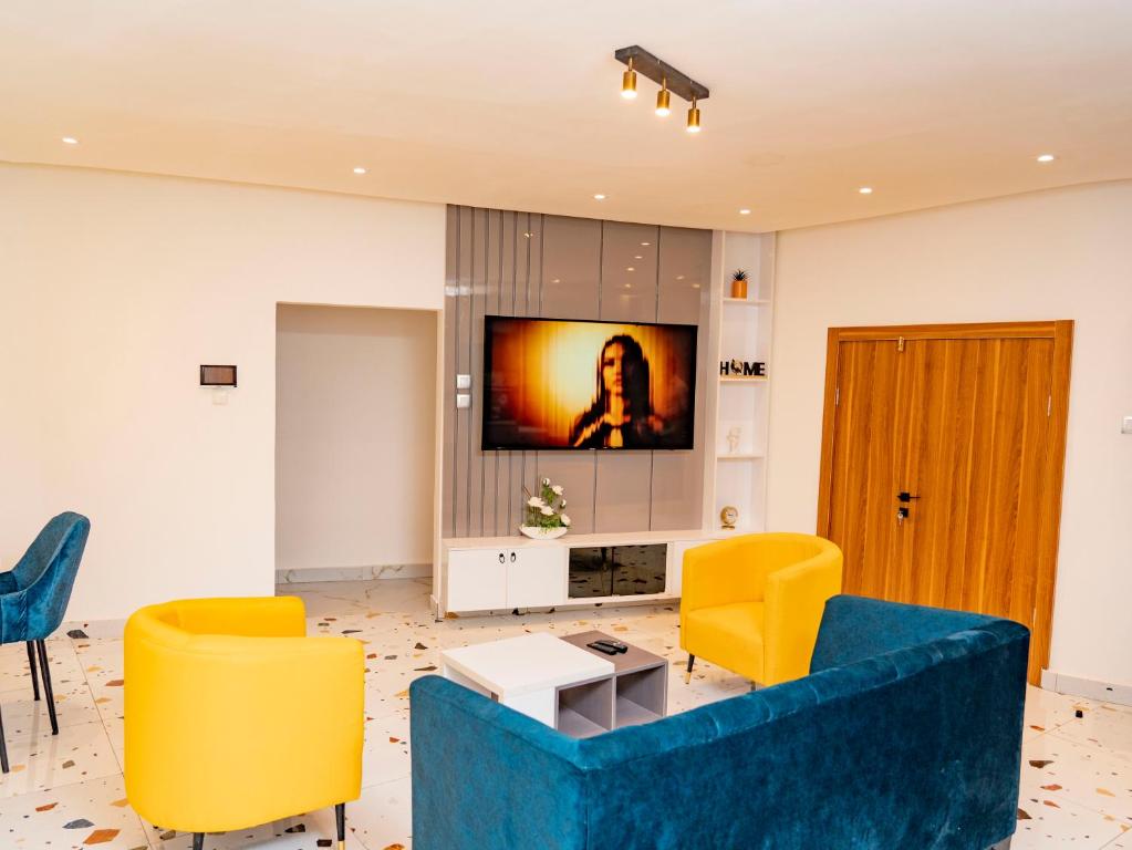a living room with a blue couch and yellow chairs at Appartement Ibiza in Cotonou