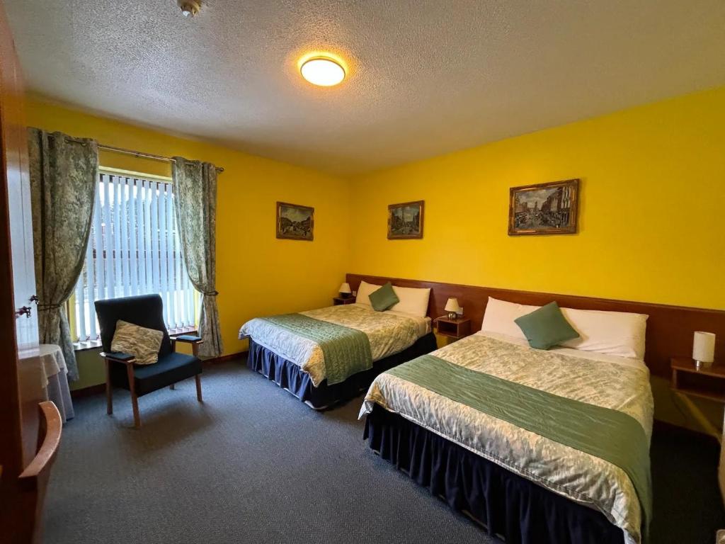 a hotel room with two beds and a chair at The Stables B&B in Antrim