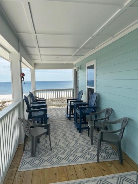 a porch with chairs and the ocean in the background at Pelican Roost E by Pristine Properties Vacation Rentals in Mexico Beach