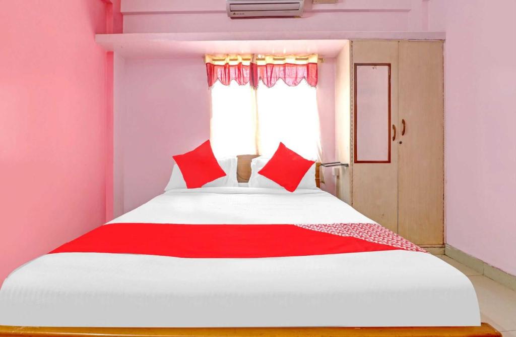 a bedroom with a large white bed with red pillows at OYO Flagship 79566 Sai Hotel in Bangalore
