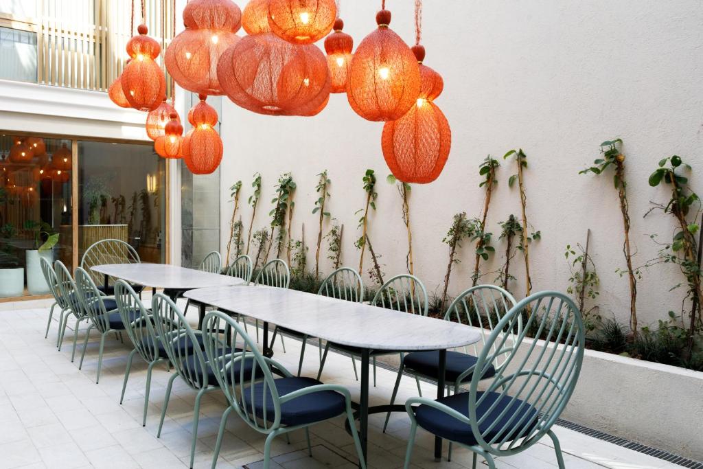 Bromelia Hotel Boutique في بوينس آيرس: مجموعة من الطاولات والكراسي مع أضواء برتقالية