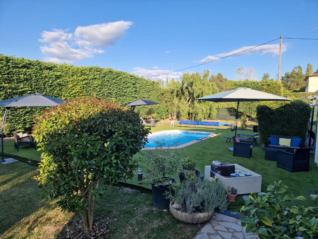 um quintal com uma piscina com guarda-sóis e plantas em L'étape Provencale em Cabriès